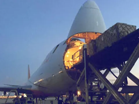A 747 freighter with its nose door open, loading cargo