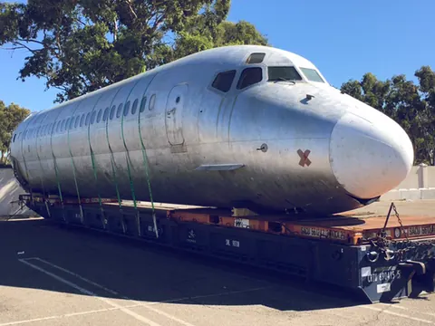 An aircraft fuselage strapped to a low trailer