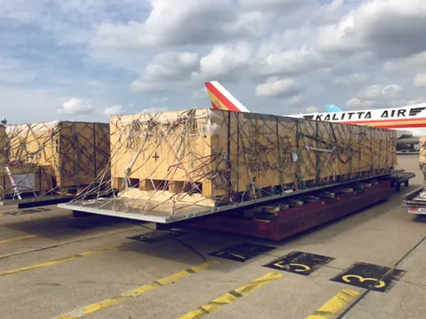 Large netted wooden crates on a loader beside a 747 freighter