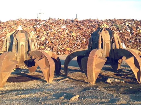 Two orange-peel grabs resting on a pile of scrap metal
